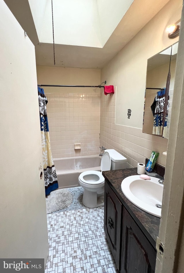 bathroom featuring toilet, shower / tub combo, vanity, and tile walls