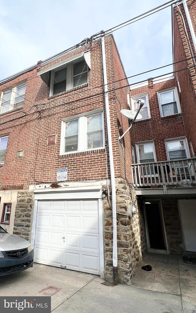 view of front facade featuring stone siding, brick siding, an attached garage, and driveway