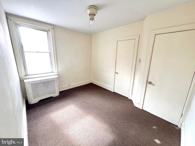 unfurnished bedroom with radiator and dark carpet