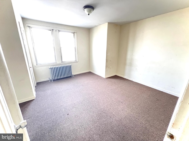 unfurnished room featuring carpet floors, radiator, and baseboards