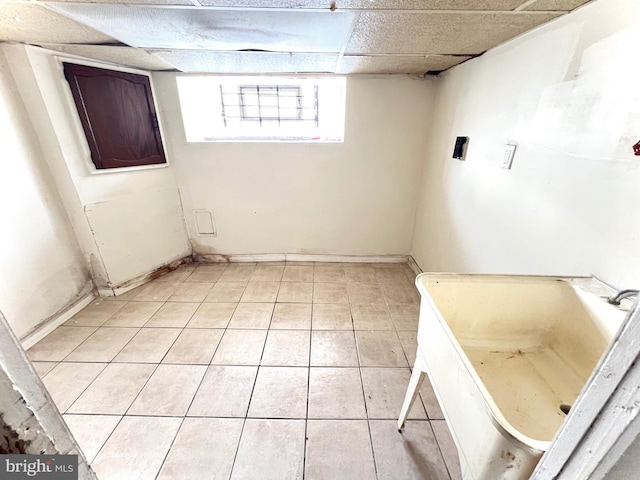 basement featuring light tile patterned flooring and a paneled ceiling