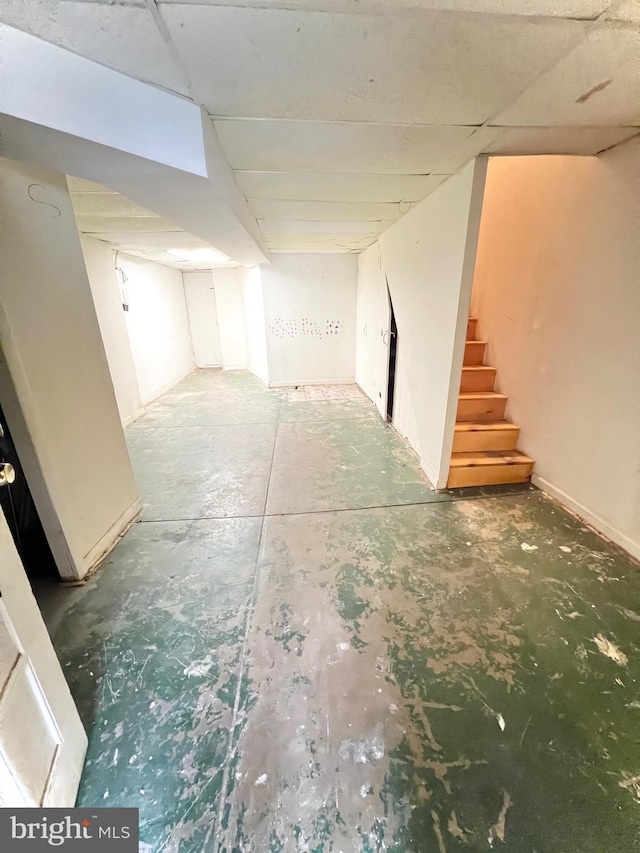 finished basement featuring a paneled ceiling and stairs