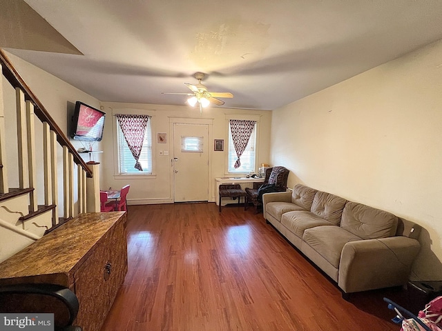 living area featuring a wealth of natural light, stairs, a ceiling fan, and wood finished floors