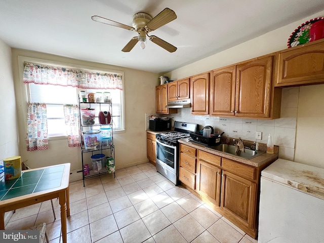 kitchen with tasteful backsplash, stainless steel gas stove, a sink, black microwave, and under cabinet range hood