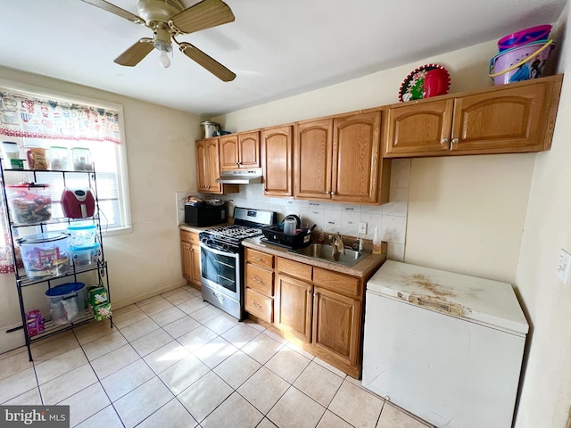 kitchen with black microwave, under cabinet range hood, light countertops, tasteful backsplash, and gas range