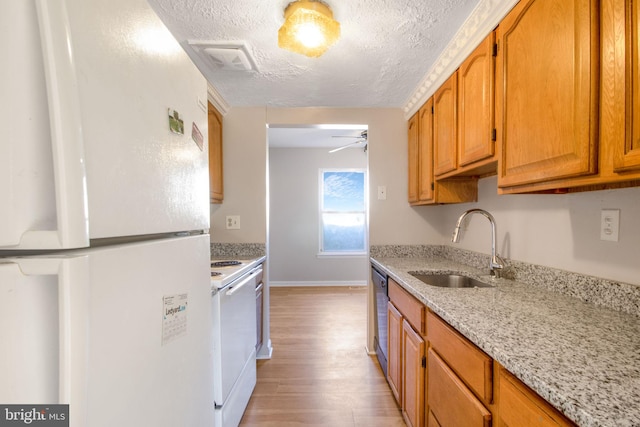 kitchen with light stone counters, sink, ceiling fan, light hardwood / wood-style flooring, and white appliances