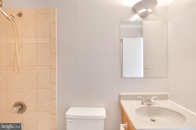 bathroom featuring toilet, vanity, and a tile shower