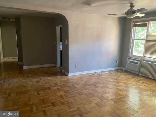 spare room with radiator, ceiling fan, and parquet floors