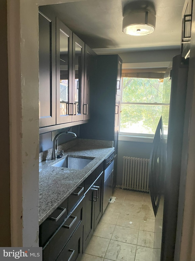 kitchen with radiator, fridge, light stone countertops, sink, and stainless steel dishwasher