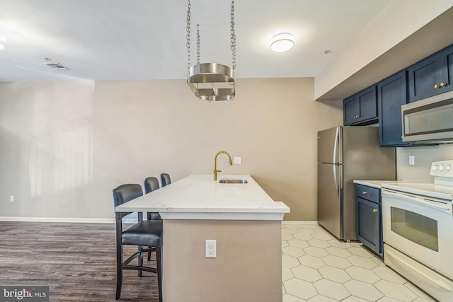 kitchen featuring light wood-type flooring, light stone counters, stainless steel appliances, a breakfast bar, and sink