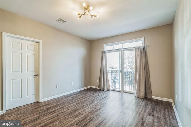 spare room featuring dark hardwood / wood-style floors and an inviting chandelier