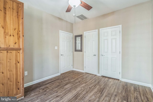 unfurnished bedroom featuring hardwood / wood-style flooring, ceiling fan, and two closets