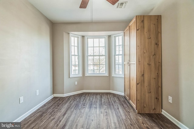 unfurnished room with ceiling fan and dark wood-type flooring