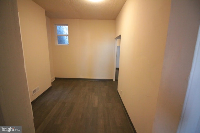 hall featuring a textured ceiling and dark hardwood / wood-style flooring