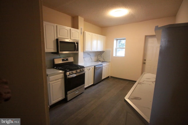 kitchen featuring dark wood-type flooring, white cabinets, stainless steel appliances, a textured ceiling, and sink