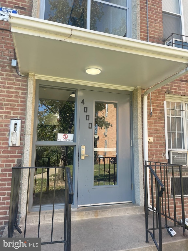 entrance to property featuring brick siding and cooling unit