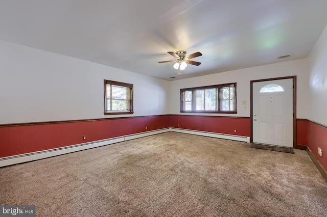 carpeted foyer with ceiling fan, a baseboard radiator, and a wealth of natural light