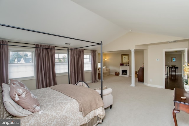 carpeted bedroom featuring vaulted ceiling and decorative columns