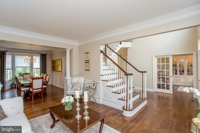 living room featuring ornate columns, an inviting chandelier, dark hardwood / wood-style floors, and ornamental molding