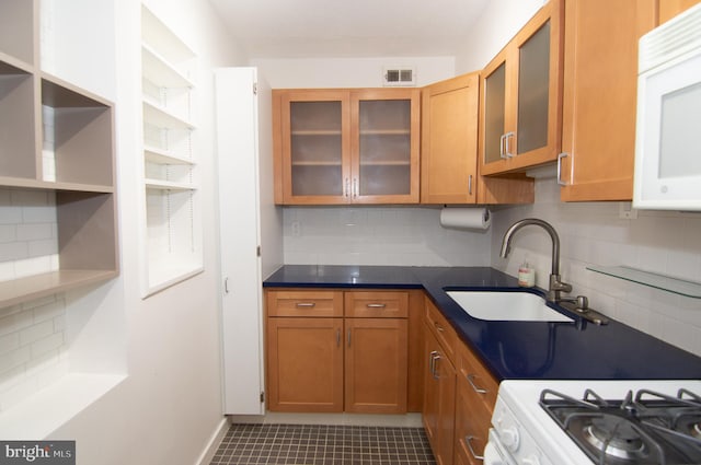 kitchen featuring white appliances, tasteful backsplash, dark tile patterned floors, and sink