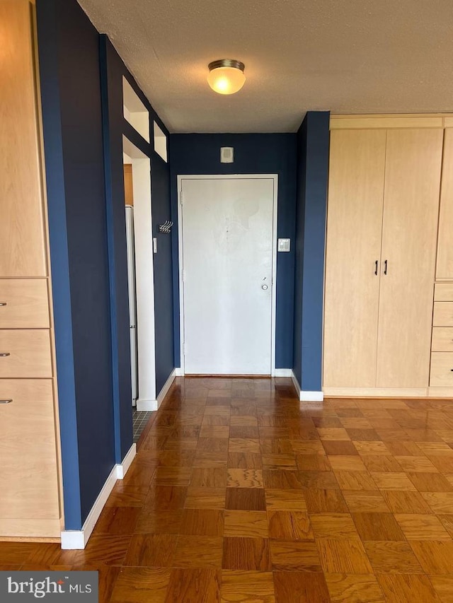 hallway featuring dark parquet flooring and a textured ceiling