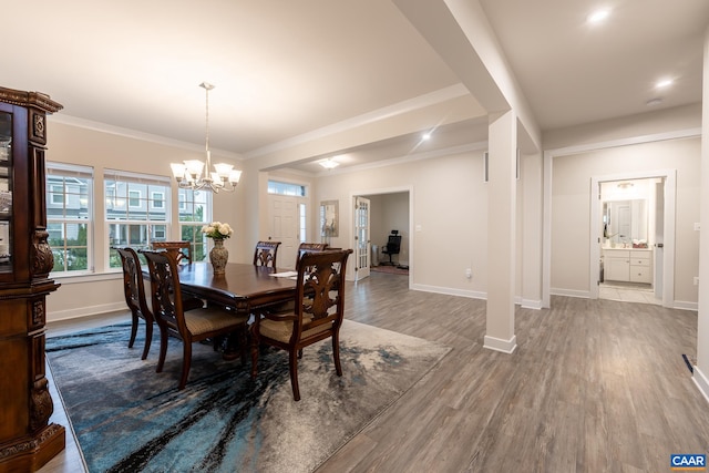 dining area with ornamental molding, wood-type flooring, and a notable chandelier