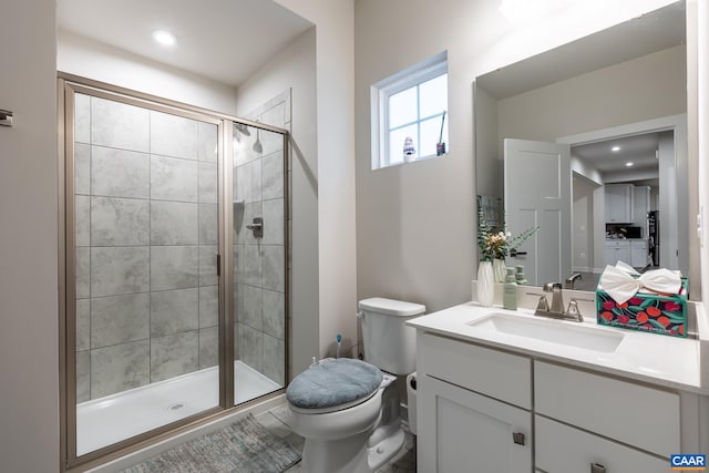 bathroom with a shower with door, vanity, and toilet