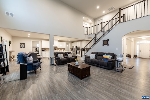 living room with wood-type flooring and a towering ceiling