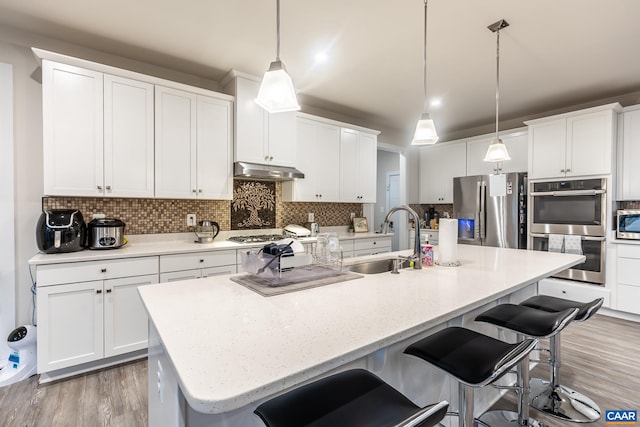 kitchen with decorative light fixtures, stainless steel appliances, sink, and white cabinetry