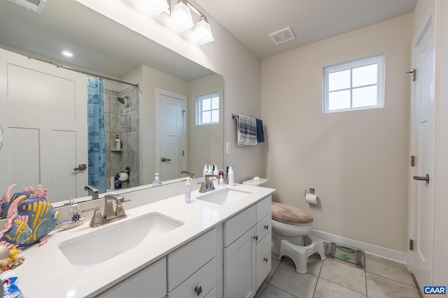 bathroom featuring a tile shower, tile patterned flooring, vanity, and toilet