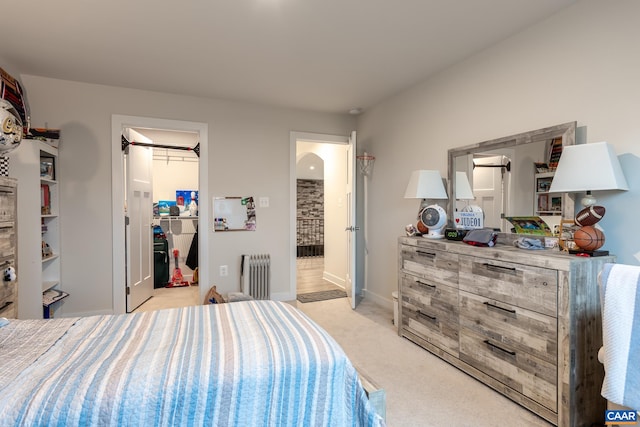 carpeted bedroom featuring radiator heating unit, a closet, and a spacious closet