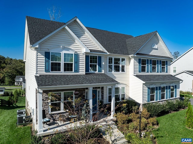 view of front of house with central AC unit and a front yard