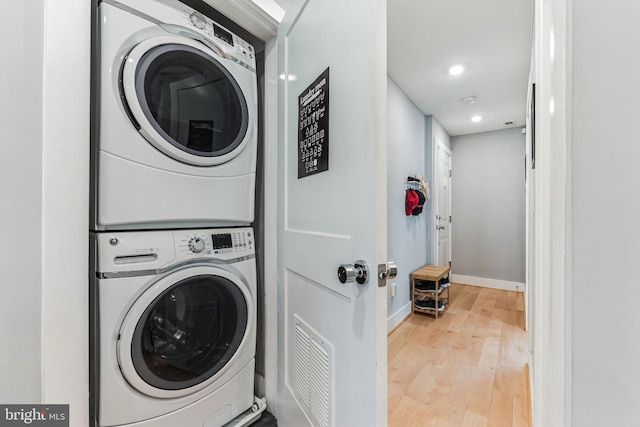 laundry room with stacked washer and dryer and hardwood / wood-style flooring