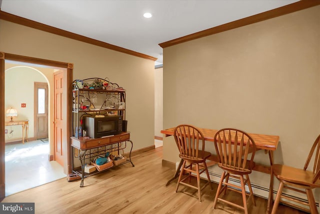 dining area with light hardwood / wood-style floors, crown molding, and a baseboard radiator