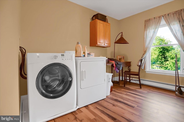 laundry area featuring washer and clothes dryer, a baseboard heating unit, light wood-type flooring, and cabinets