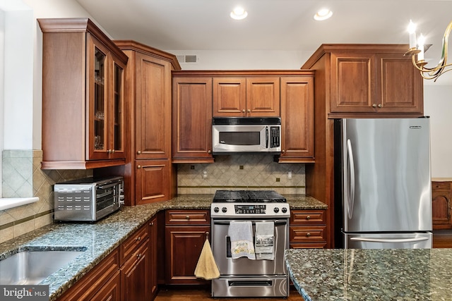 kitchen featuring tasteful backsplash, dark stone countertops, appliances with stainless steel finishes, and hardwood / wood-style flooring