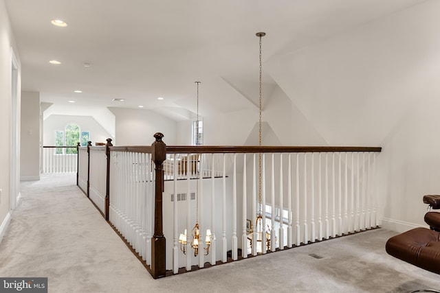 corridor with vaulted ceiling, a notable chandelier, and light carpet