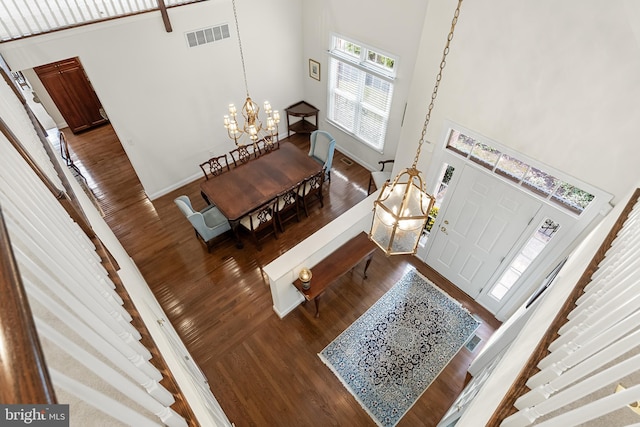 interior space featuring hardwood / wood-style flooring, a towering ceiling, and a notable chandelier