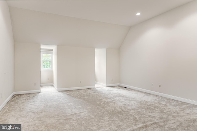 empty room featuring light colored carpet and lofted ceiling