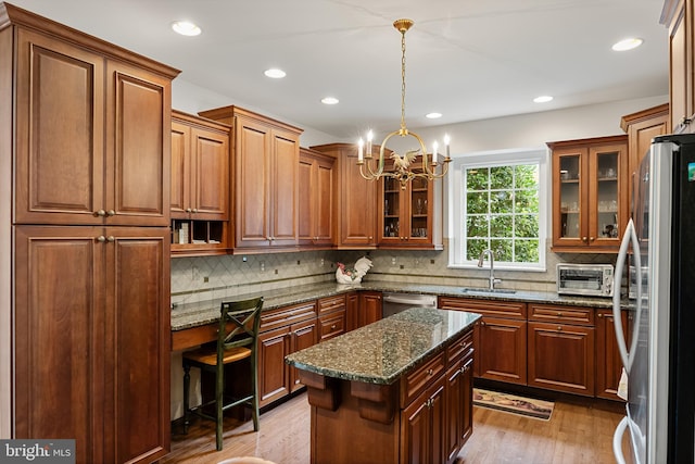 kitchen featuring dark stone counters, sink, hanging light fixtures, appliances with stainless steel finishes, and a center island