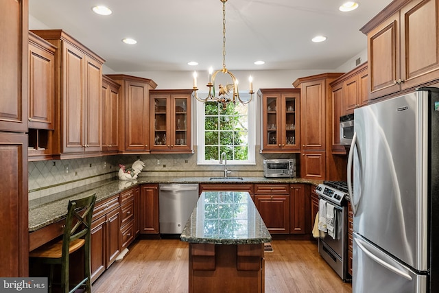 kitchen with a kitchen island, stainless steel appliances, sink, light hardwood / wood-style floors, and stone counters