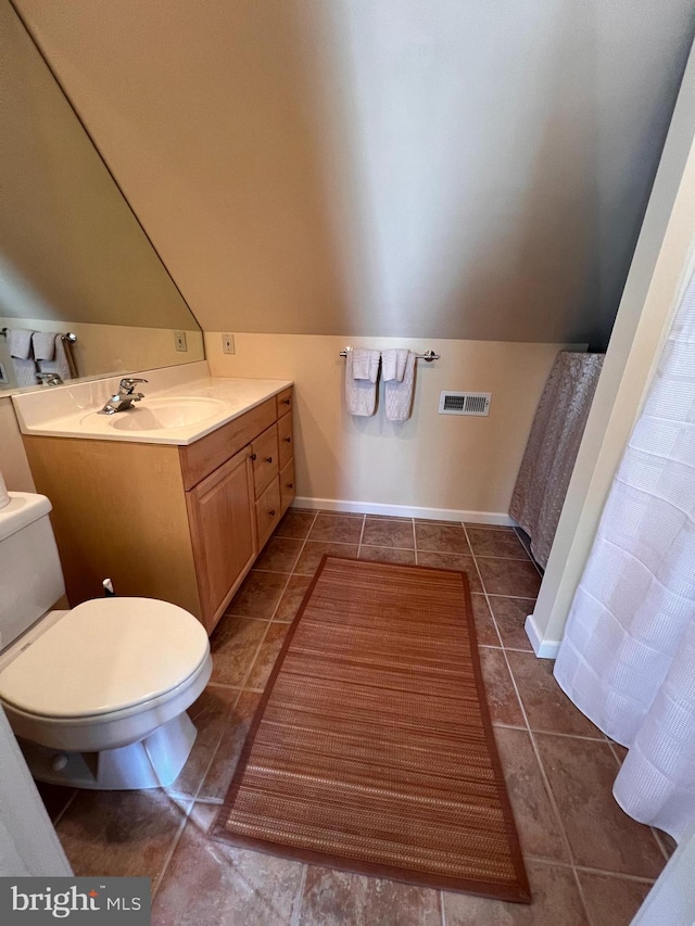 bathroom with tile patterned flooring, lofted ceiling, toilet, and vanity