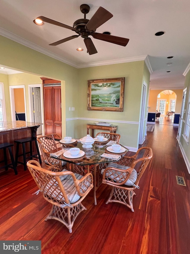 dining room with dark wood-type flooring, ceiling fan, and ornamental molding