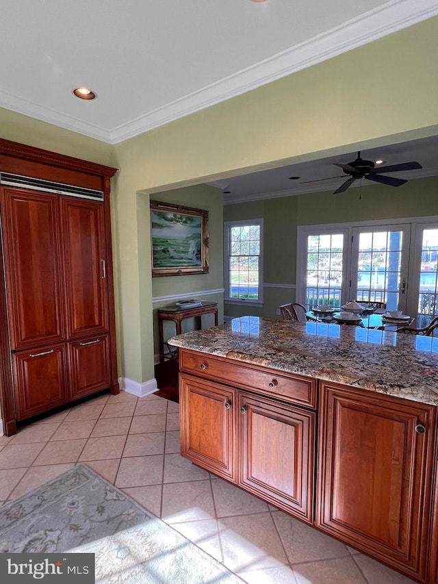 kitchen featuring ornamental molding, dark stone counters, ceiling fan, and light tile patterned floors