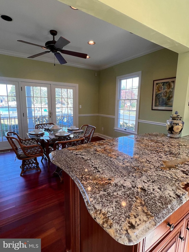 kitchen featuring dark wood-type flooring, ceiling fan, crown molding, and light stone countertops