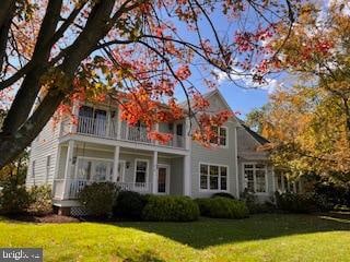 rear view of house with a balcony and a yard