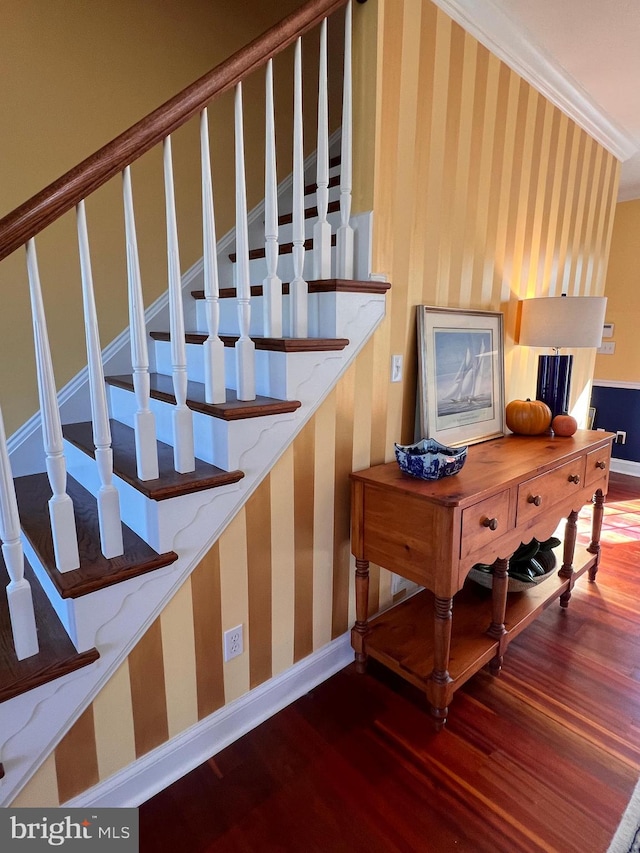 stairway with wood-type flooring and ornamental molding