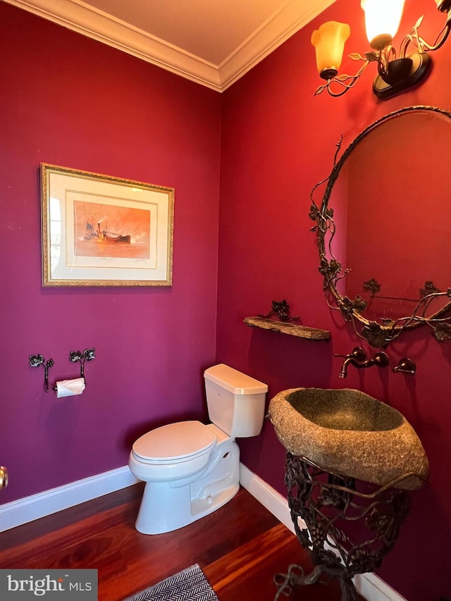 bathroom featuring hardwood / wood-style flooring, toilet, and ornamental molding