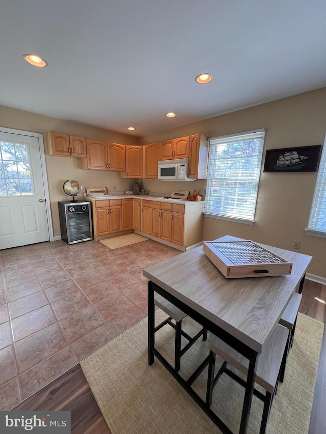 kitchen featuring light brown cabinets, a wealth of natural light, light hardwood / wood-style floors, and wine cooler