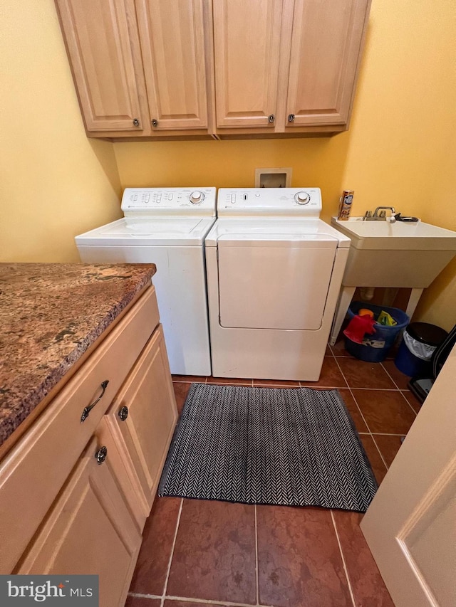 clothes washing area featuring cabinets, washing machine and dryer, sink, and dark tile patterned flooring